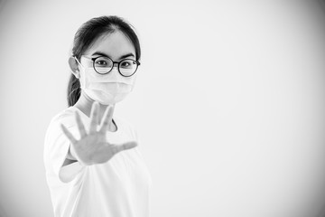 Black and white color portrait Asian young woman wears glasses and mask to protect against Coronavirus, girl show hand stop coronavirus outbreak, copy space for stop virus Covid 19 concept background