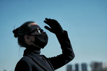 Young girl in a black protective mask and black sunglasses on the street, protecting against the virus