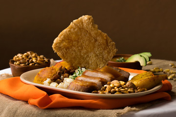 Fritada, fried pork, typical Ecuadorian dish served with potato tortillas, toast, mote