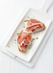 Sandwich with soft cheese and ham. Bright wooden background. Top view. 