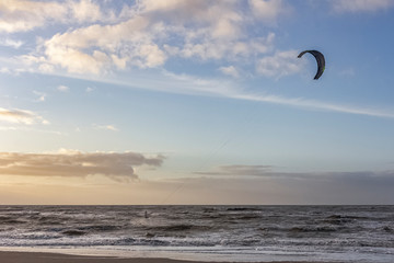 View of the north sea beach on a windy winter day at sunset, people, kitesurfing. Noordwijk, the Netherlands