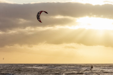 View of the north sea beach on a windy winter day at sunset, people, kitesurfing. Noordwijk, the Netherlands