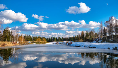 Spring landscape. Forest lake with reflection of clouds and trees growing along the shore,...