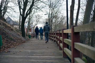 Fototapeta na wymiar Four guys stand on the bridge near the river