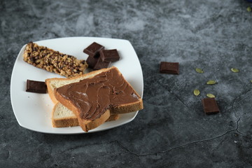 Chocolate cream toast with bitter chocolate pieces around on a piece of marble