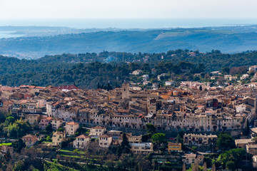 Fototapeta premium A close-up panoramic view of the old medieval French town Vence with the low Alps mountains hills, the Mediterranean Sea and forests in the background (Provence / Riviera / Côte d'Azur)