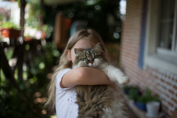 Little girl holding a fluffy cat in her arms