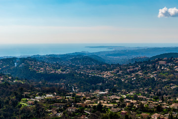 A close-up panoramic view of the old medieval French town Vence and other town's buildings with the low Alps mountains hills and the Mediterranean Sea on the horizon (Provence / Riviera / Côte d'Azur)