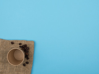 Disposable cups and coffee beans on a blue background.
