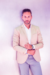 Portrait of Young Businessman in New York City. Young European Businessman with beard, wearing white shirt, beige jacket, standing against silver metal wall, looking forward. Color filtered effect..