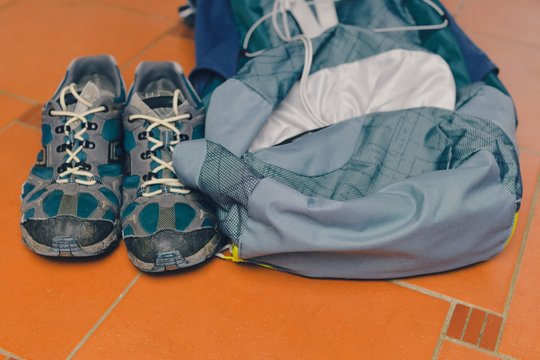 Hiking equipment: backpack and trekking boots on the floor. Horizontal photo and brown background. Tourist backgrounds and still-life. Preparation and planning for the travelling. Concept of the