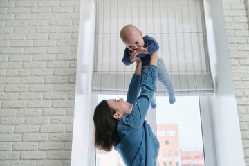 Happy young beautiful mother playing with toddler son