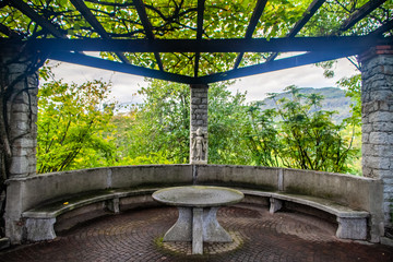 Un pergolato con tavolo di marmo e panca nel giardino botanico di Villa Taranto, Verbania, Italia