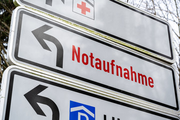 Direction sign shows the Red Cross and German text Notaufnahme, meaning emergency department, at...