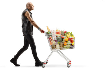 Bald punk walking with a shopping cart full of food