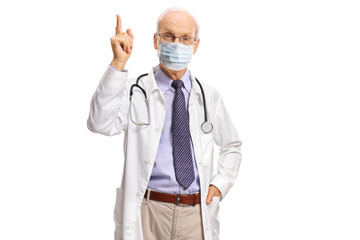 Elderly doctor with a medical face mask pointing up with his finger