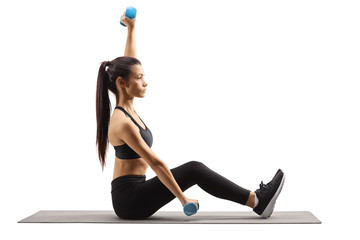 Young woman exercising with dumbbells on a mat
