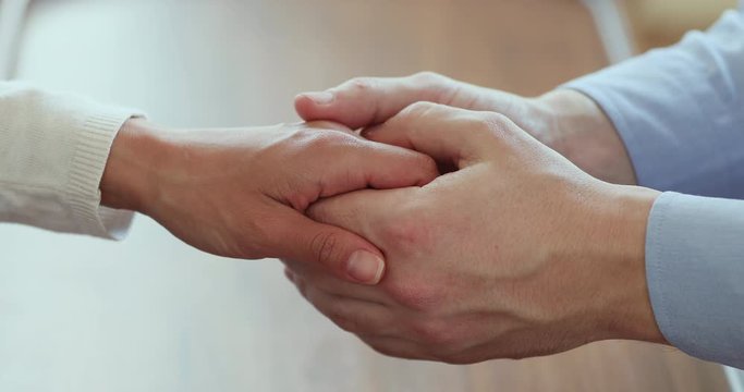 Family couple holding hands expressing support in marriage relationship. Caring young man friend husband giving comfort and empathy to woman, infertile wife, having miscarriage concept. Close up view