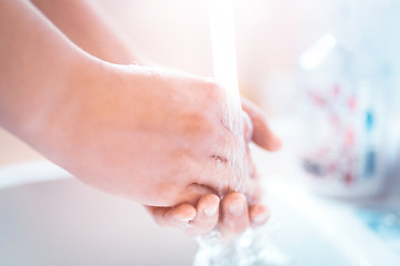 Naklejka premium Washing hands under running water using soap, important step for a good hygiene