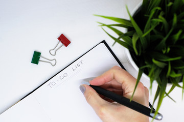 Hand holding a pen and writing a to-do list