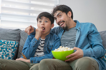 Padre e hijo viendo tv en el sillón de la sala