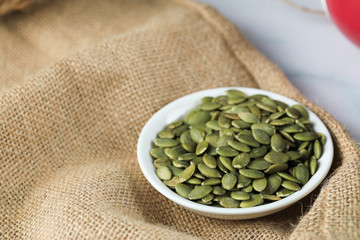 Green fresh pumpkin seeds in a white saucer
