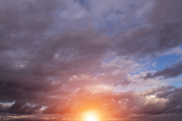 Epic dramatic sunset, sunrise on storm sky with dark clouds, orange yellow sun and sunlight, heaven