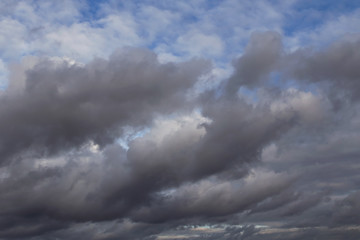 Cumulus fluffy white and dark grey storm clouds against blue sky background, heaven	