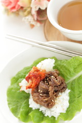 Korean food, grilled beef and kimchi on rice wrapped by lettuce