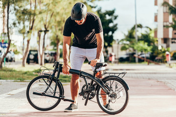 Young man preparing his folding bicycle outdoors