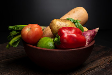 cuenco de madera con verduras frescas, papas zapallo tomate cebolla de verdeo batata verdras frescas y naturales 