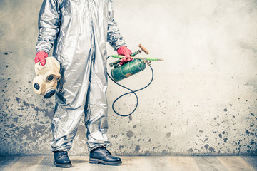 Pest control worker in protective uniform with vintage disinfectant sprayer and old respirator gas mask. Preventing the spread of disease respiratory syncytial virus coronavirus COVID-19. Retro style - obrazy, fototapety, plakaty