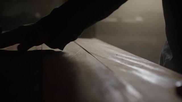 Mann arbeitet mit Holzbrettern in einer staubigen Werkstatt