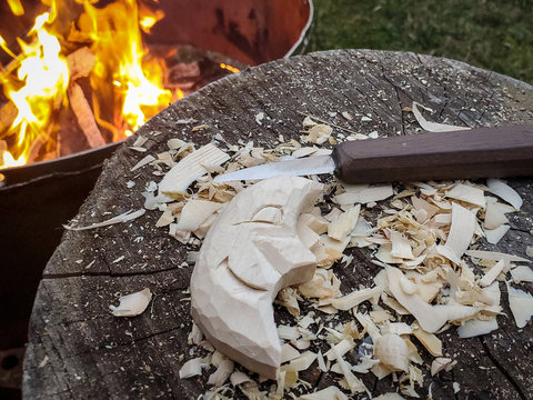 hand carved smiling moon with knife and fire in background 