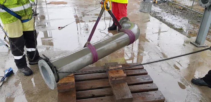 Riggers move the pipe using two chain blocks