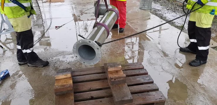 Riggers move the pipe using two chain blocks