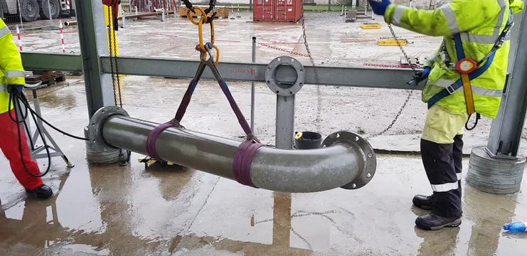 Riggers move the pipe using two chain blocks