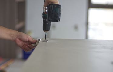 A electric drill is making a hole on a wooden door with blur background