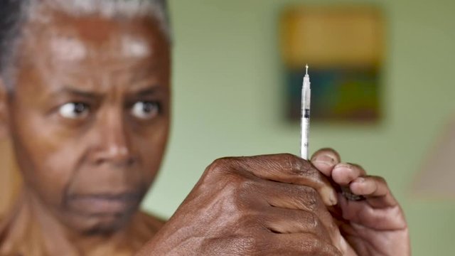 African American woman with diabetes giving herself an insulin injection