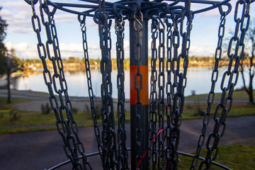 closeup view of chains on a disc golf course neark a lake in a park outside