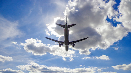 Low-Angle View of Commercial Aircraft Soaring Overhead with Clouds Above