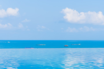 Fototapeta na wymiar Beautiful infinity outdoor swimming pool with sea ocean view around white cloud blue sky
