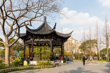 Obraz na płótnie Canvas Wangjiang Pavilion of traditional Chinese style at Jiangwan Park in historical, old town Jiangwanzhen, Hongkou, Shanghai, China, with people in face masks spending leisure time amid Covid-19.