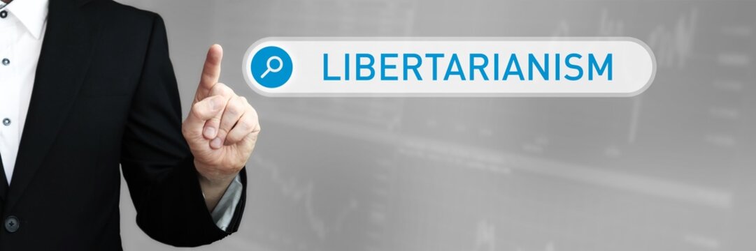 Libertarianism. Man In A Suit Points A Finger At A Search Box. The Word Libertarianism Is In The Search. Symbol For Business, Finance, Statistics, Analysis, Economy