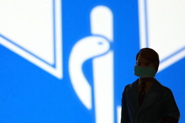 Miniature figure businessman model wearing mask stand in front of hospital sign background scene.