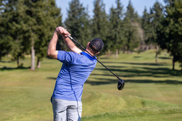 Male golfer hitting a drive on a golf course