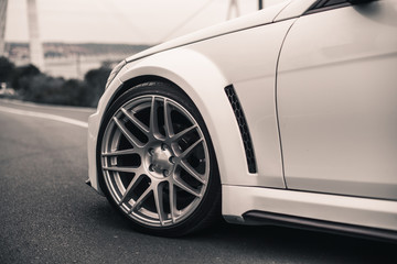 Obraz na płótnie Canvas Front wheel of a white sedan car parked on the road