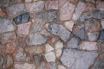 Stone wall for the backdrop. Flat stones of various colors and shapes. Cement gray seam.