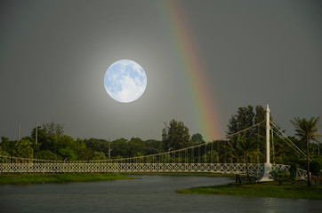 Big white moon and rainbow over the park in early evening