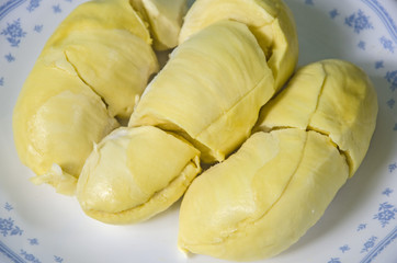 Yummy yellow aril of durian fruit in white dish close up